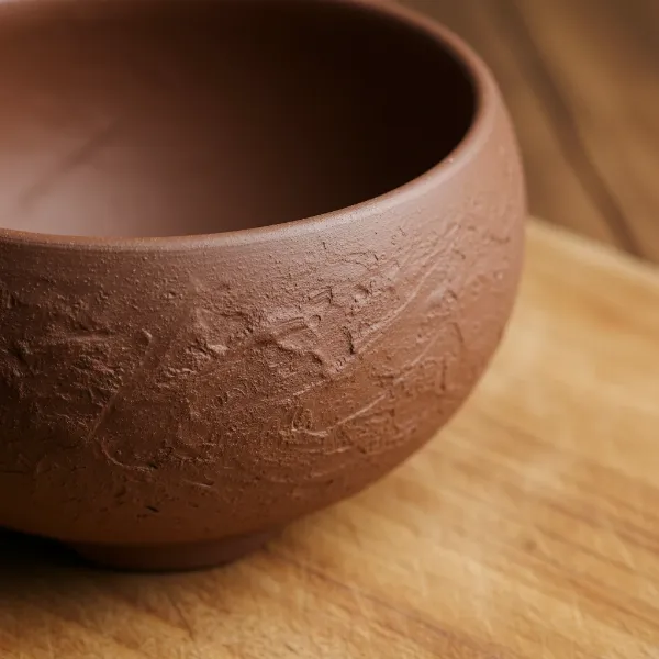 Close-up of an unglazed Zisha clay cooking pot, emphasizing its natural, porous texture and healthy material.