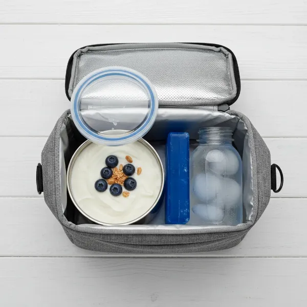 An open insulated lunch bag showing a container of yogurt, an ice pack, and a frozen water bottle.